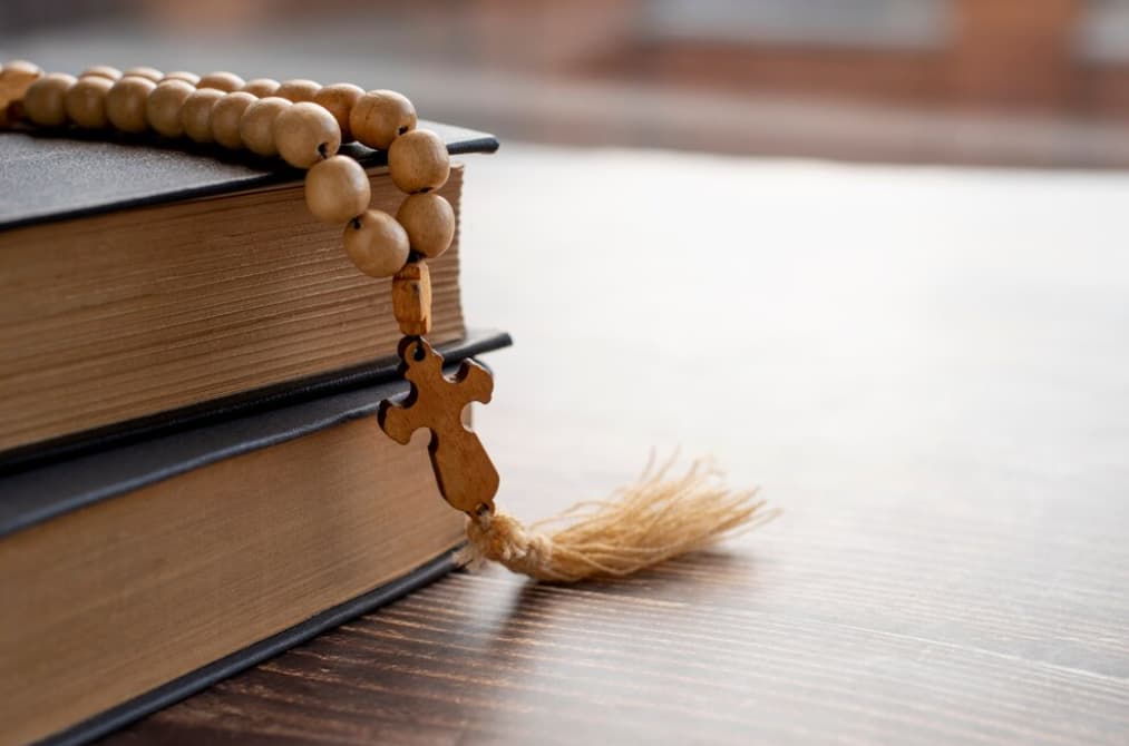 Un rosario de madera descansa sobre la esquina de un libro cerrado