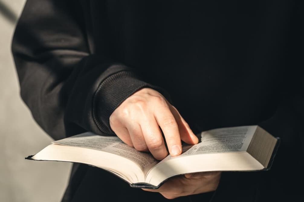 Una persona sostiene un libro abierto señalando una línea
